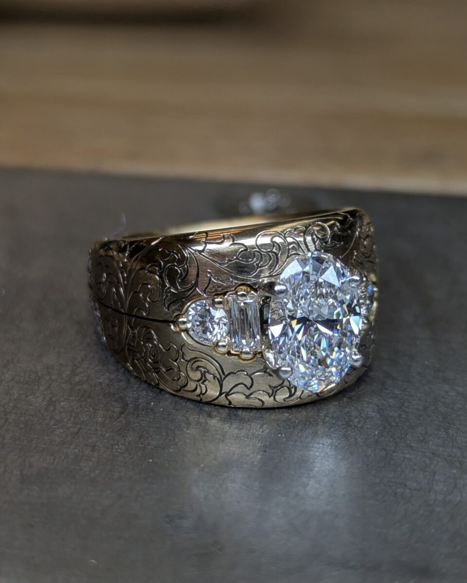 Finished custom ring: oval diamond with baguette accents set into a hand-engraved wide yellow gold band