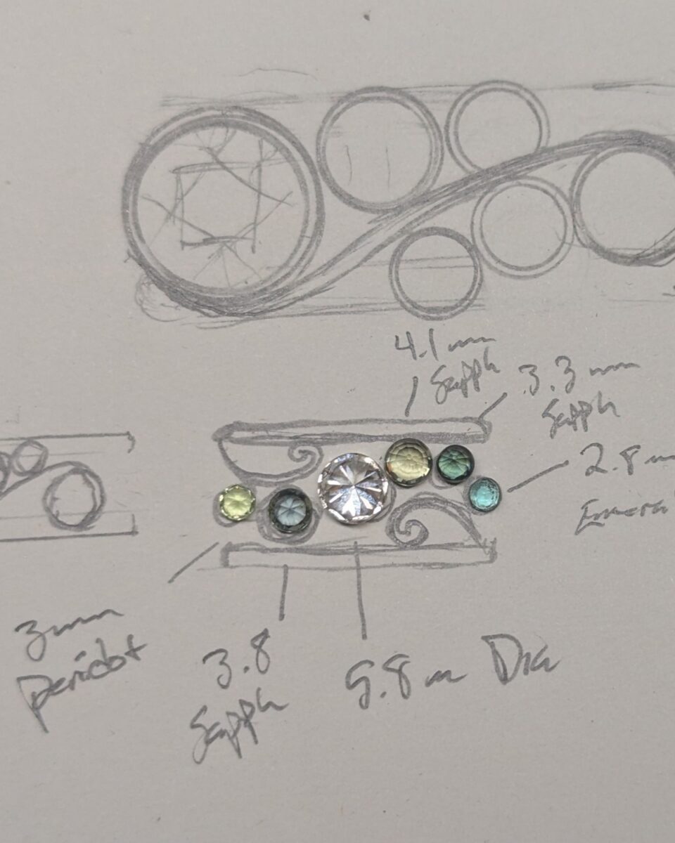 Hand-drawn band design study with loose sapphires, peridot and emerald laid out to scale beside a diamond